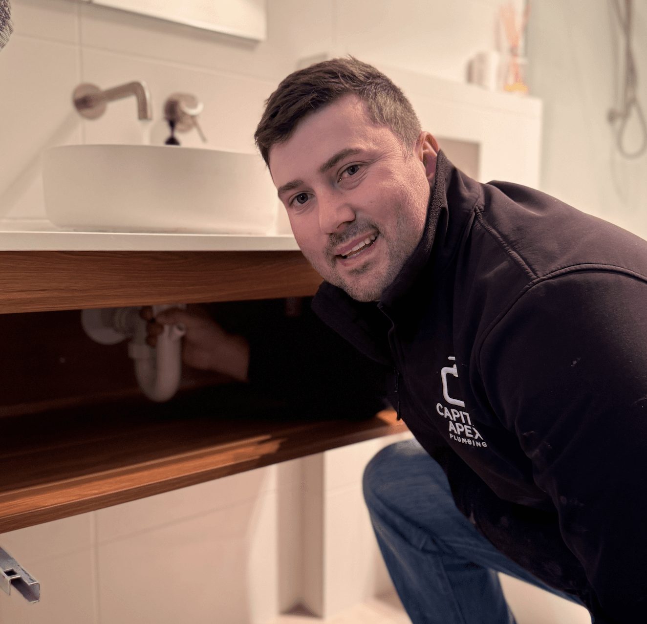 Connor diagnosing plumbing under a kitchen sink